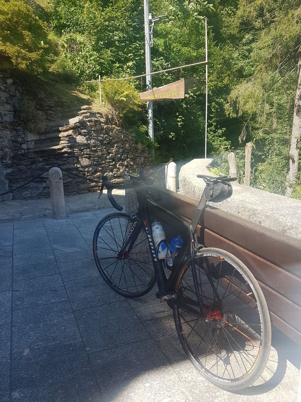 A road bike leaning against a stone wall on a café terrace in the mountains