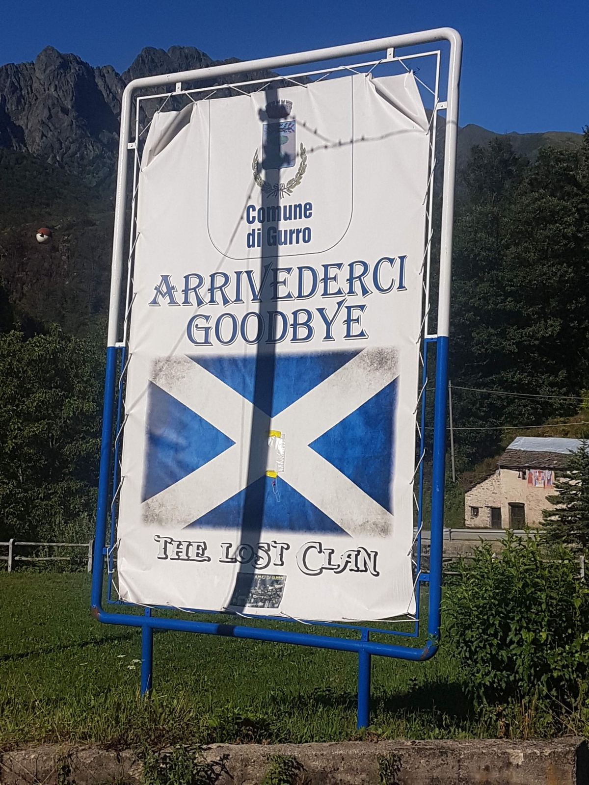A sign with the Scottish saltire flag reading Arrivederci, Goodbye, at the edge of Gurro