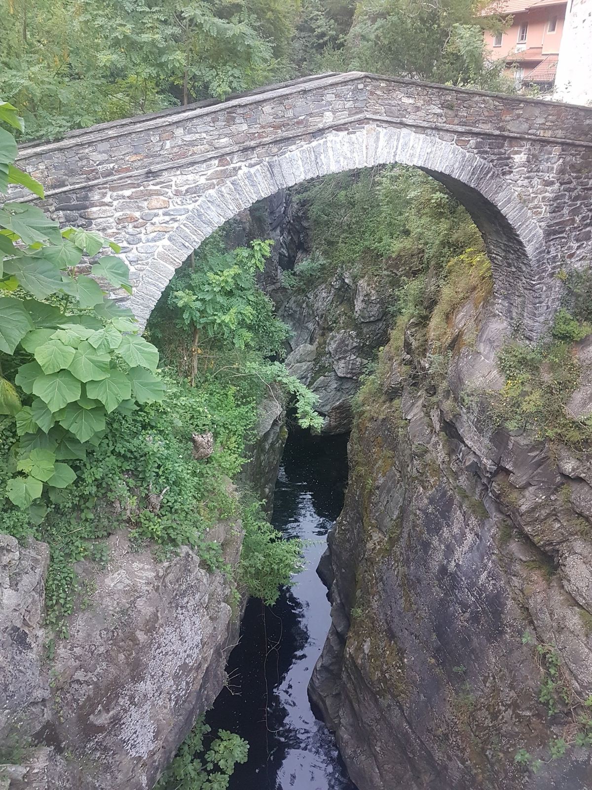 An old stone arched bridge spanning a deep narrow gorge with the river far below