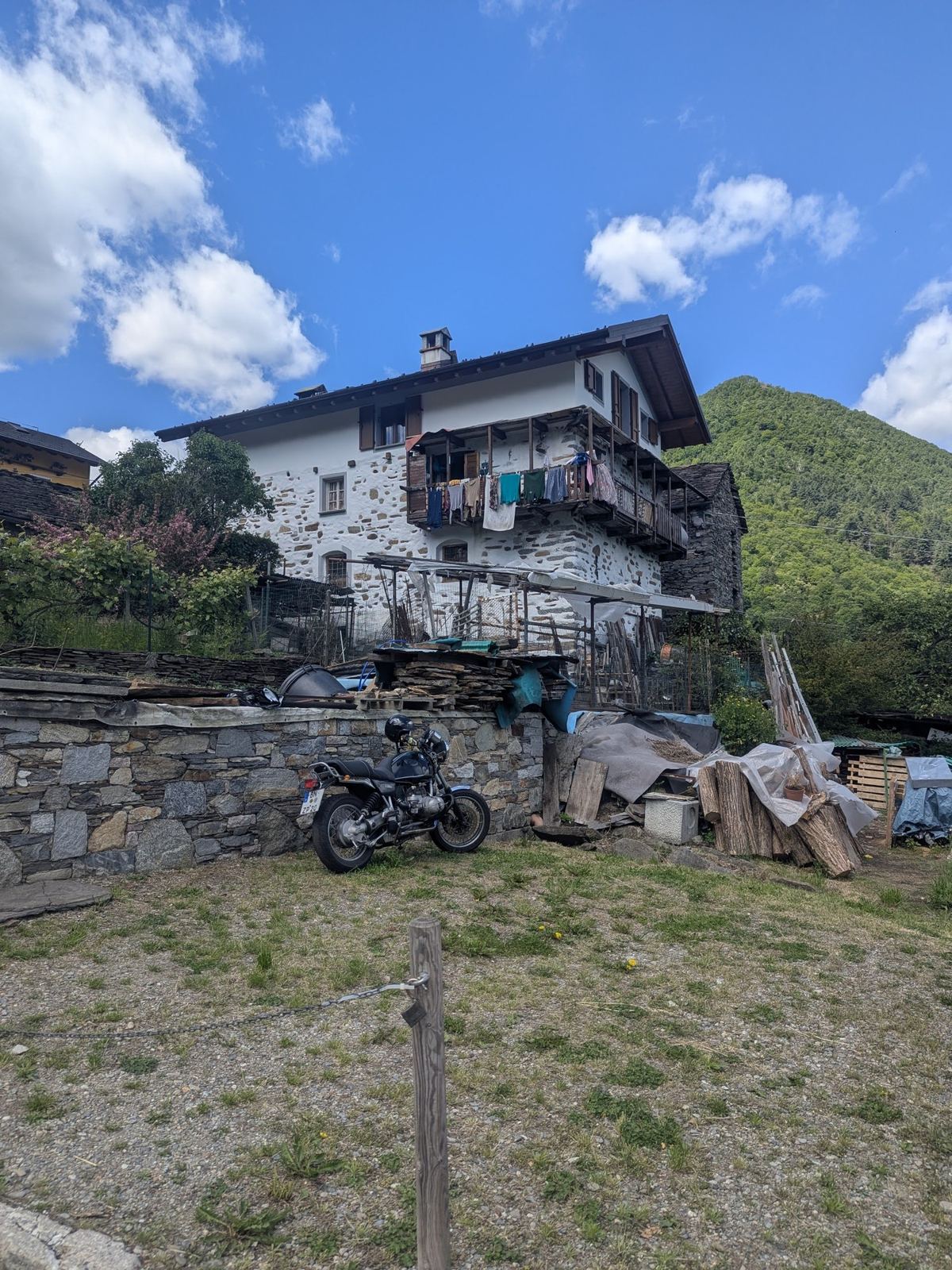 A bike leaning against a stone wall below an old stone house in Crealla