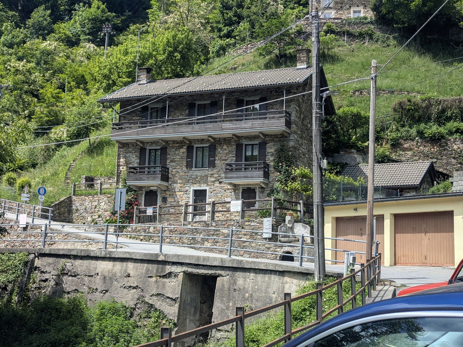 Tall old stone houses with balconies and garages beside the road in Falmenta