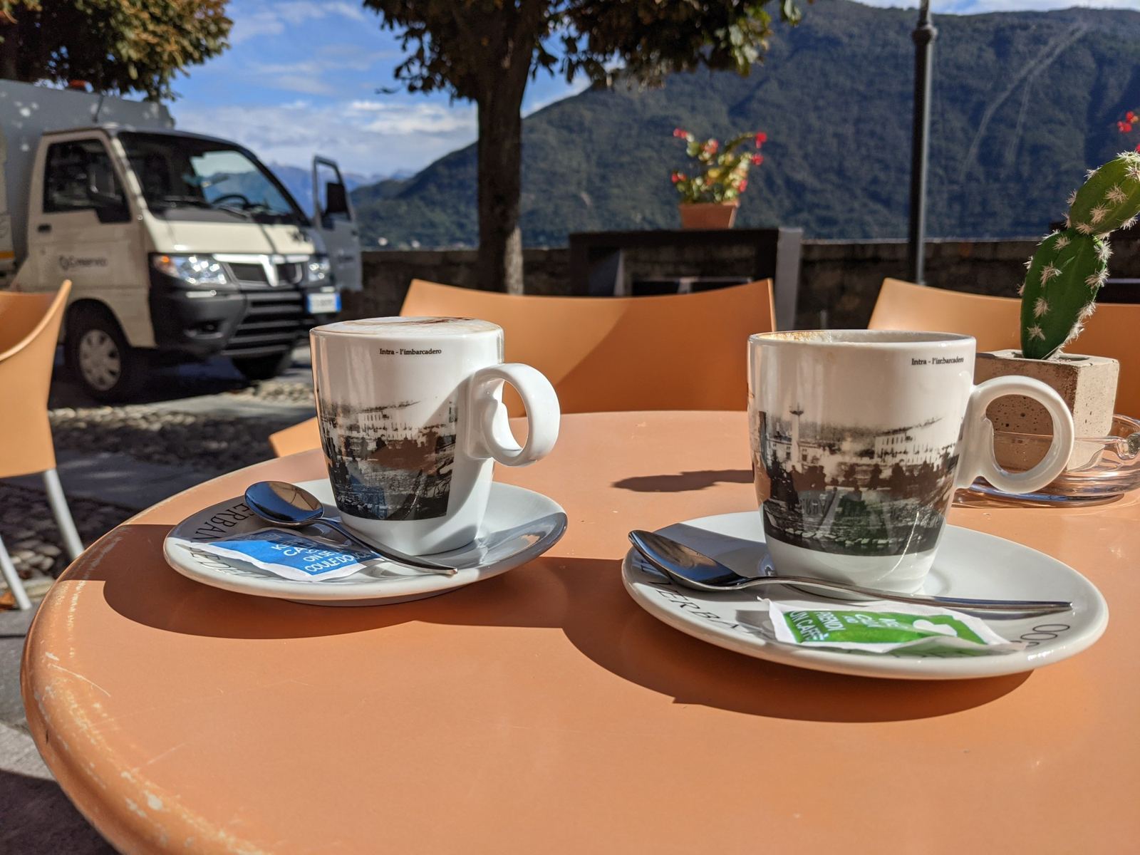 Two coffees on a café table by the lake at Cannobio with mountains behind