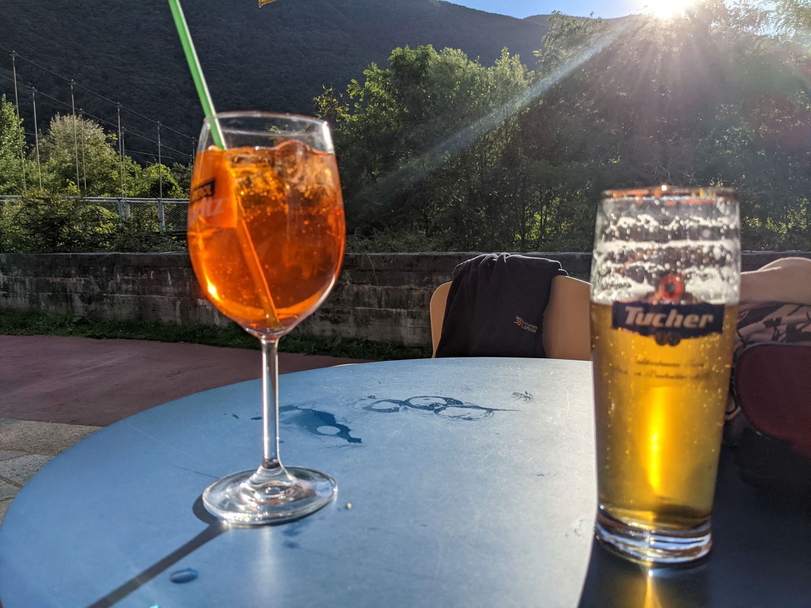 An Aperol spritz and a beer on a table in the evening sun by Lake Maggiore