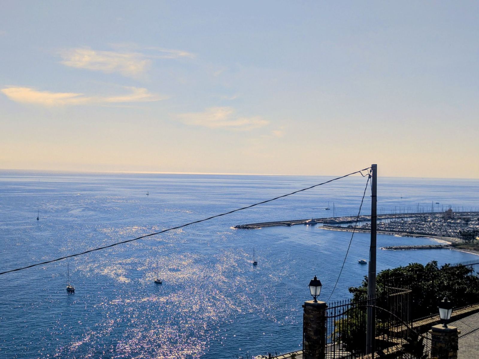 The coast and a harbour seen from above Cipressa in hazy afternoon light