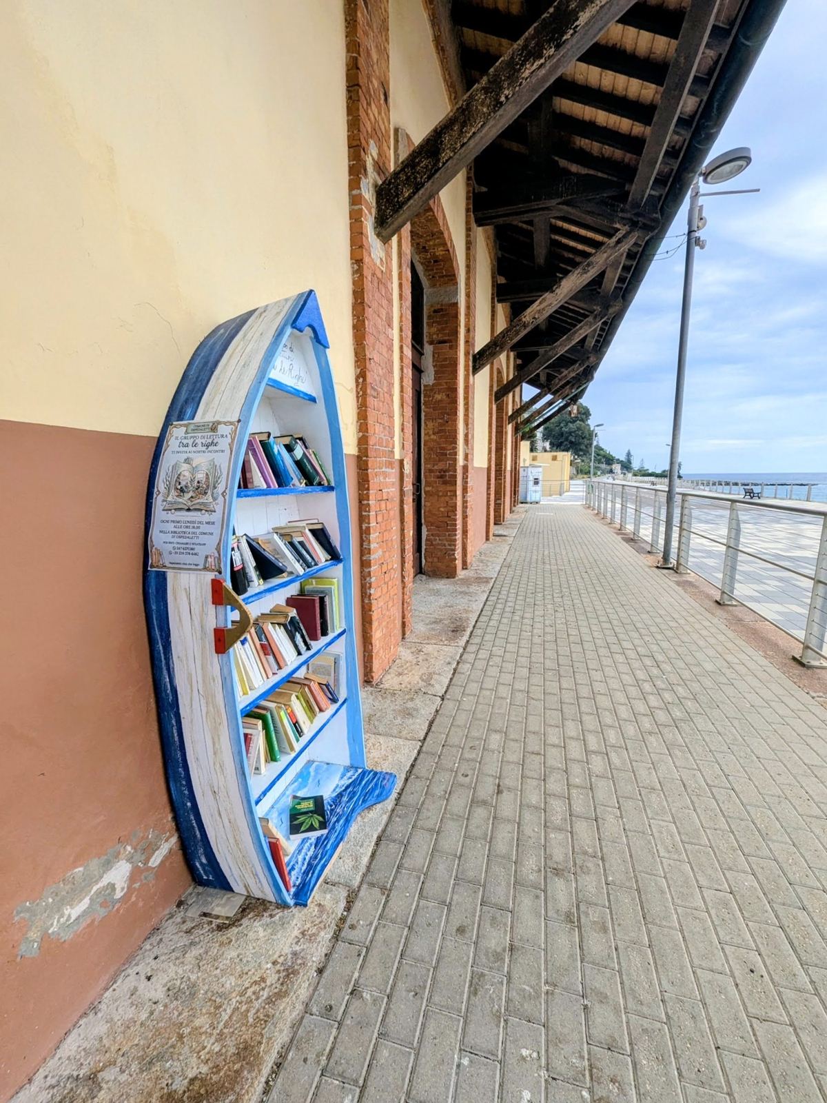 A small blue boat-shaped bookcase on the platform of an old station beside the cycle path