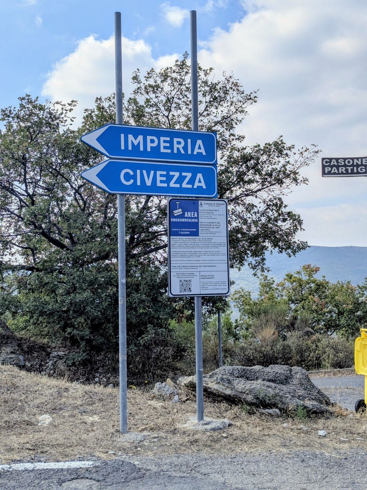 Blue road signs pointing to Imperia and Civezza at the top of the climb