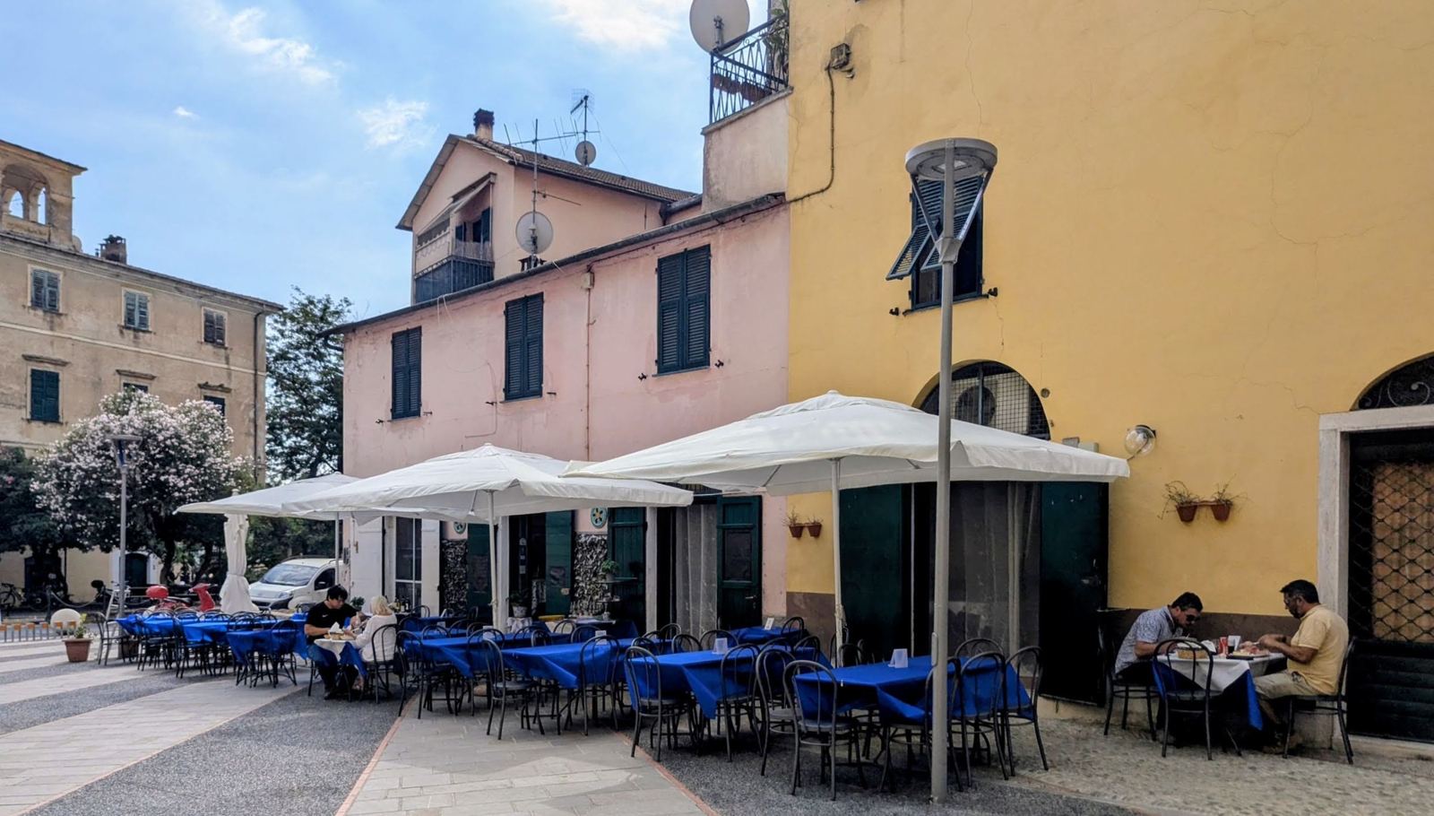 Café tables with blue cloths in the colourful piazza at Dolcedo