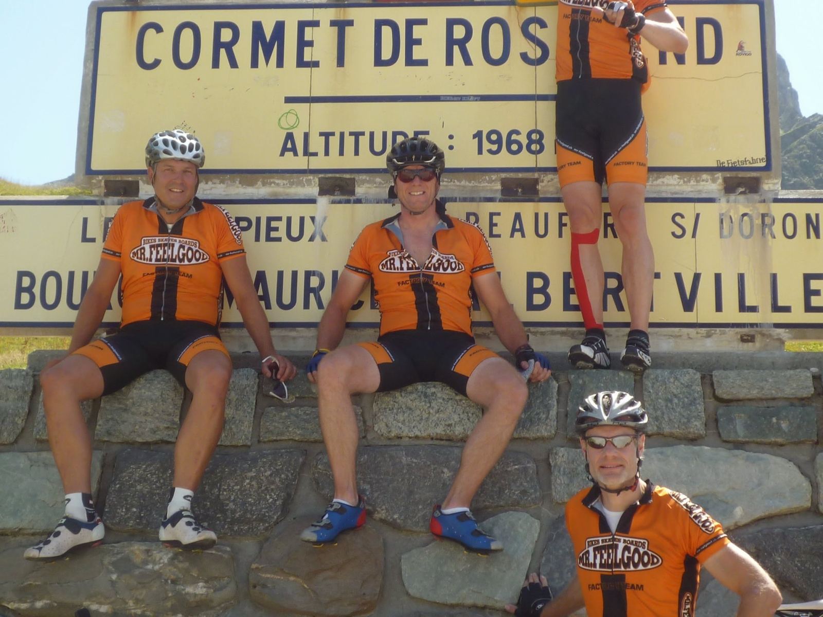 Three cyclists sitting on the Cormet de Roselend summit sign