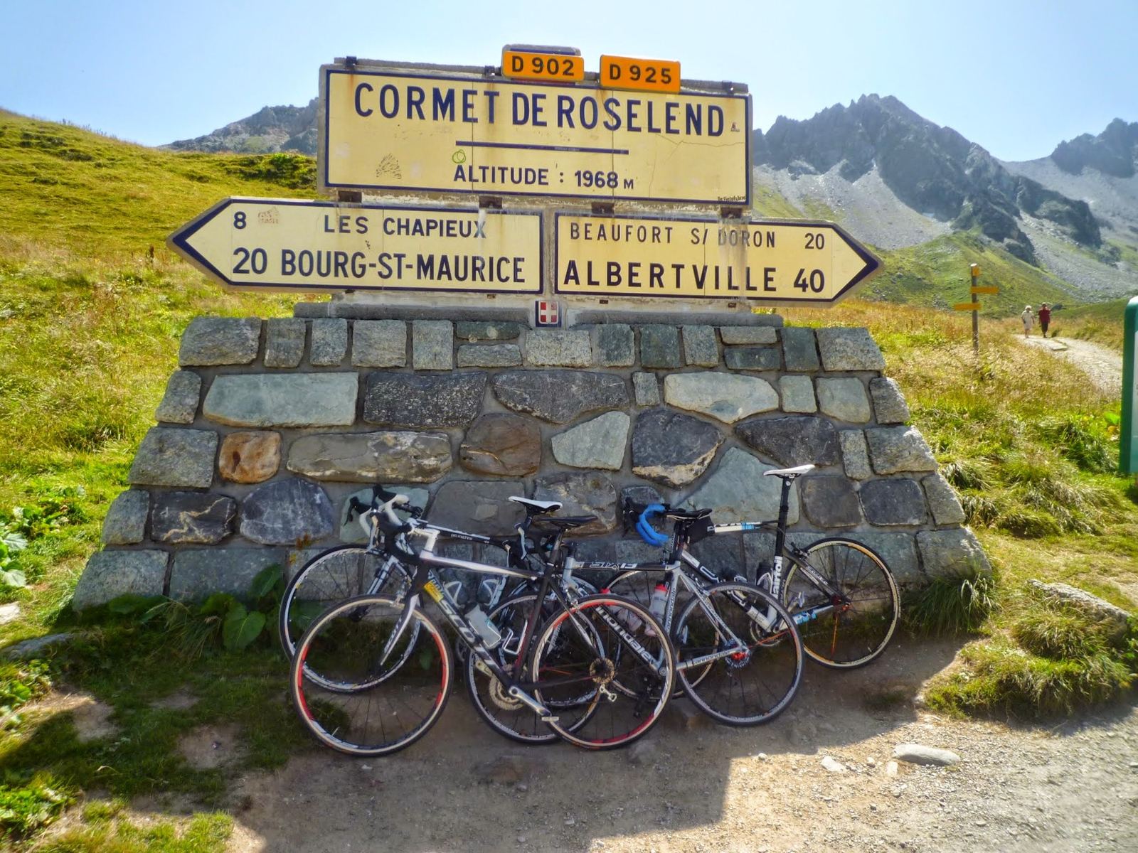 The Cormet de Roselend summit sign, altitude 1968m, with bikes leaning on the stone base