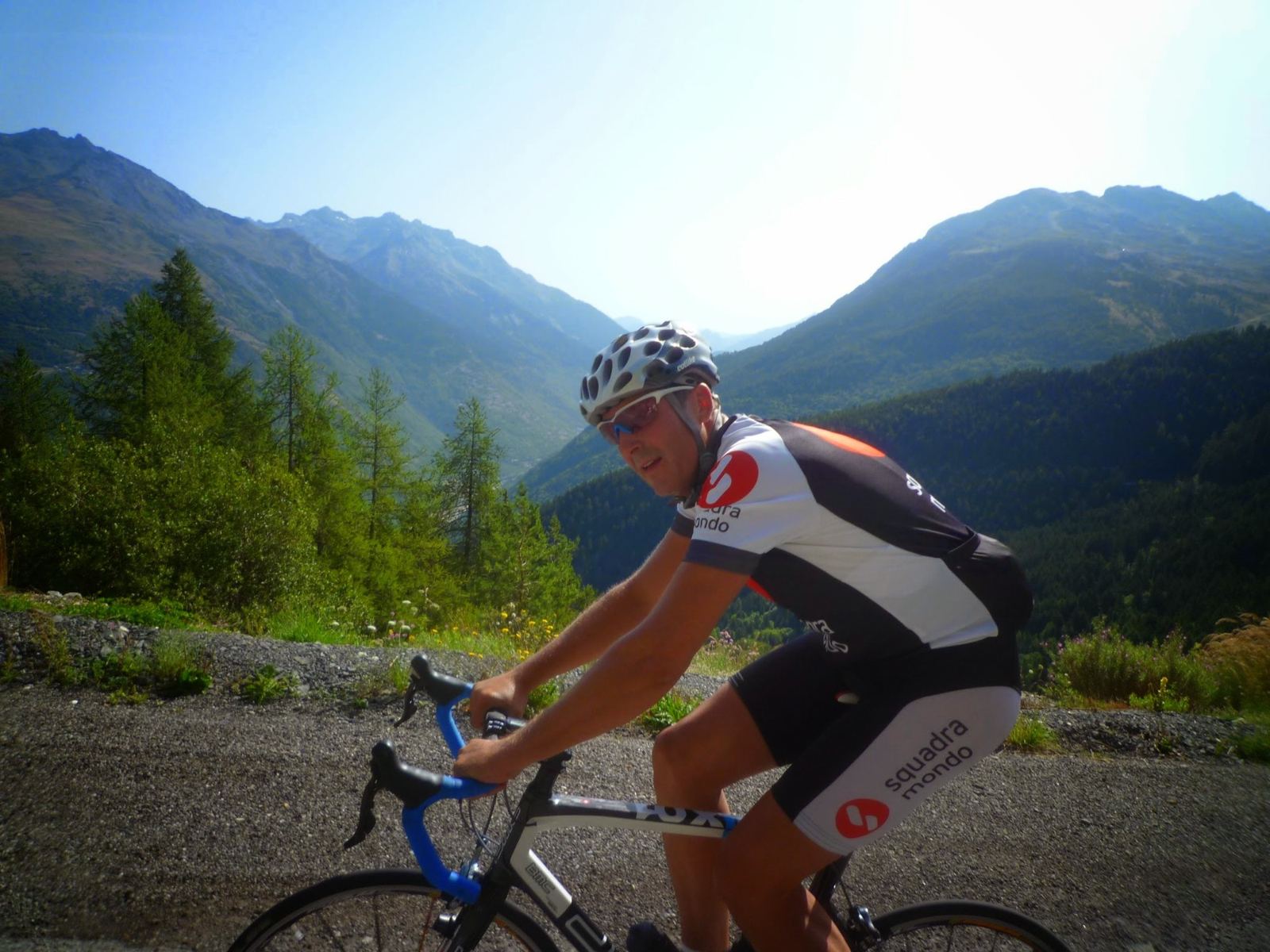 A cyclist in a Squadra Mondo jersey climbing the Télégraphe with mountains behind