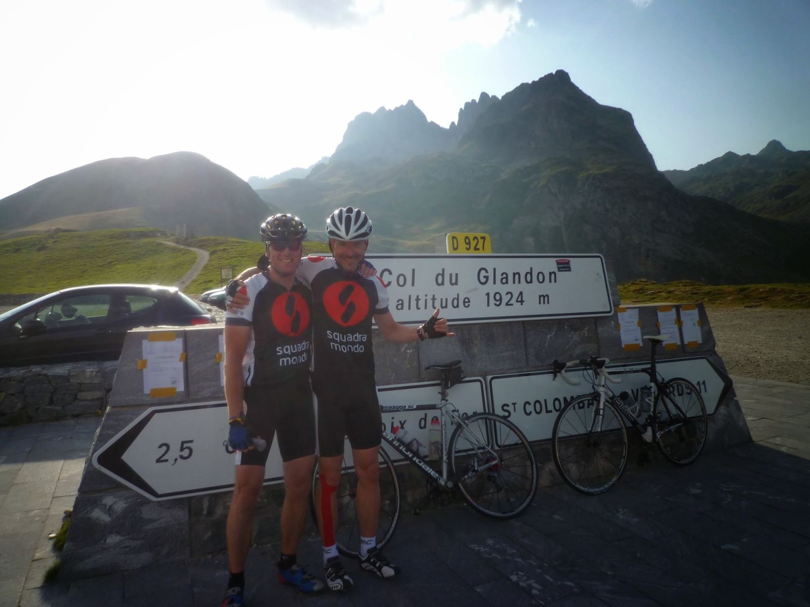 Two cyclists with their bikes at the Col du Glandon sign, altitude 1924m