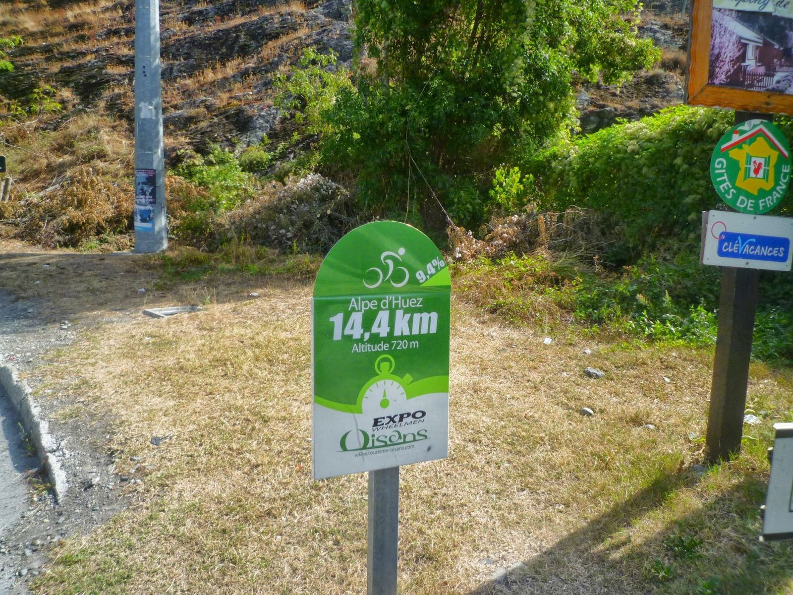 A green board at the foot of Alpe d'Huez showing 14.4km to the top