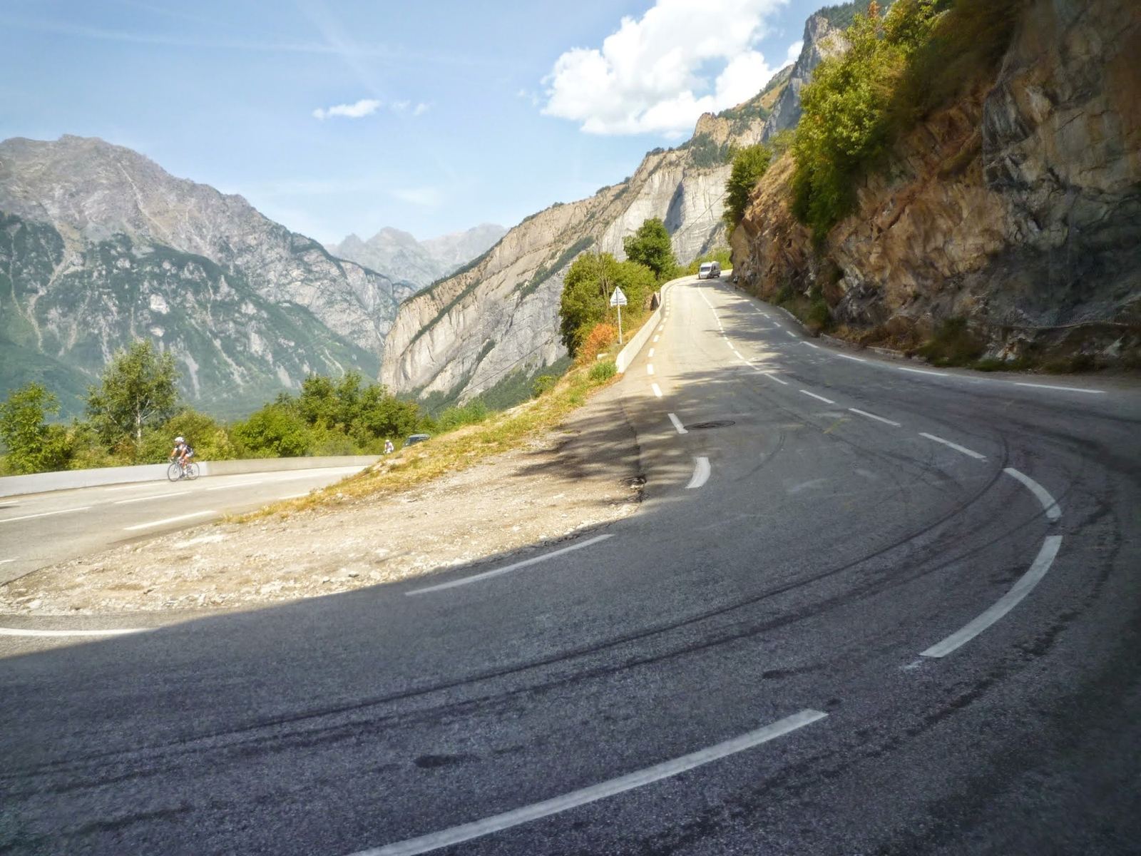 Cyclists climbing the hairpins of Alpe d'Huez with the valley and mountains behind