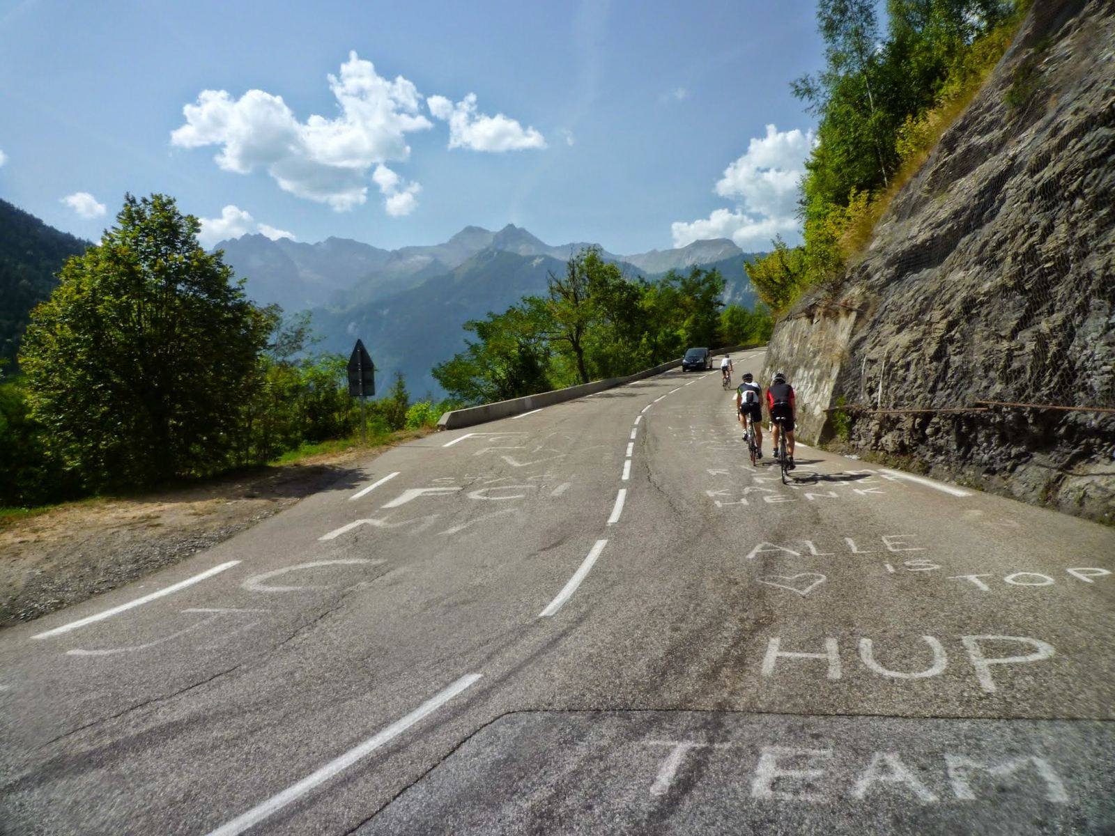 A cyclist on the Alpe d'Huez road with painted names on the tarmac