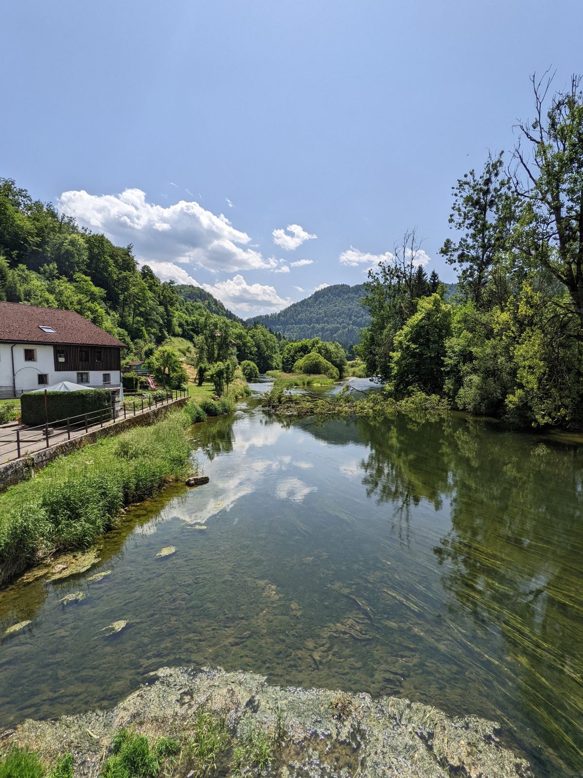 The Doubs at Goumois with clear water over stones and houses on the bank