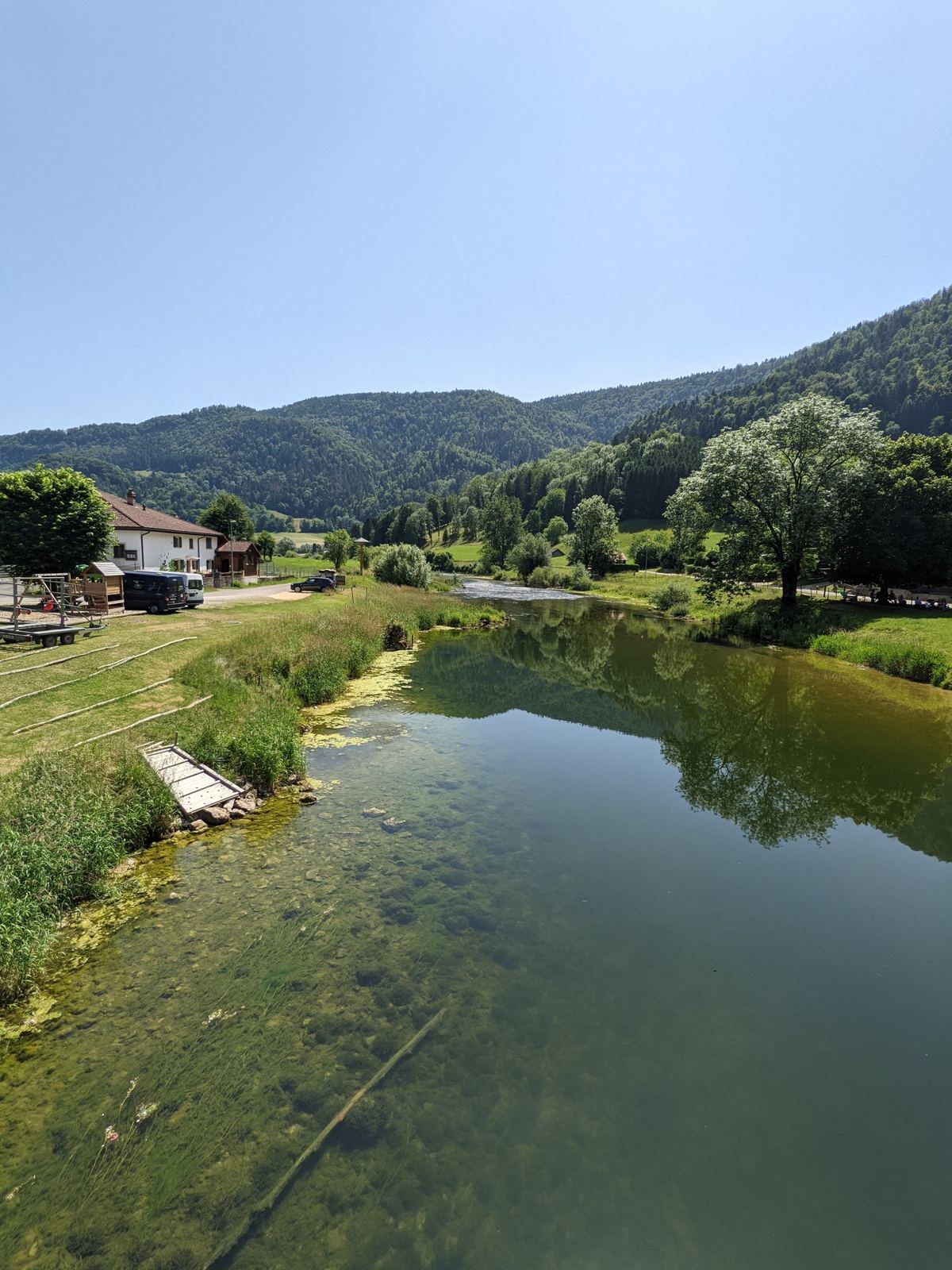 The calm Doubs at Soubey reflecting trees and the hills