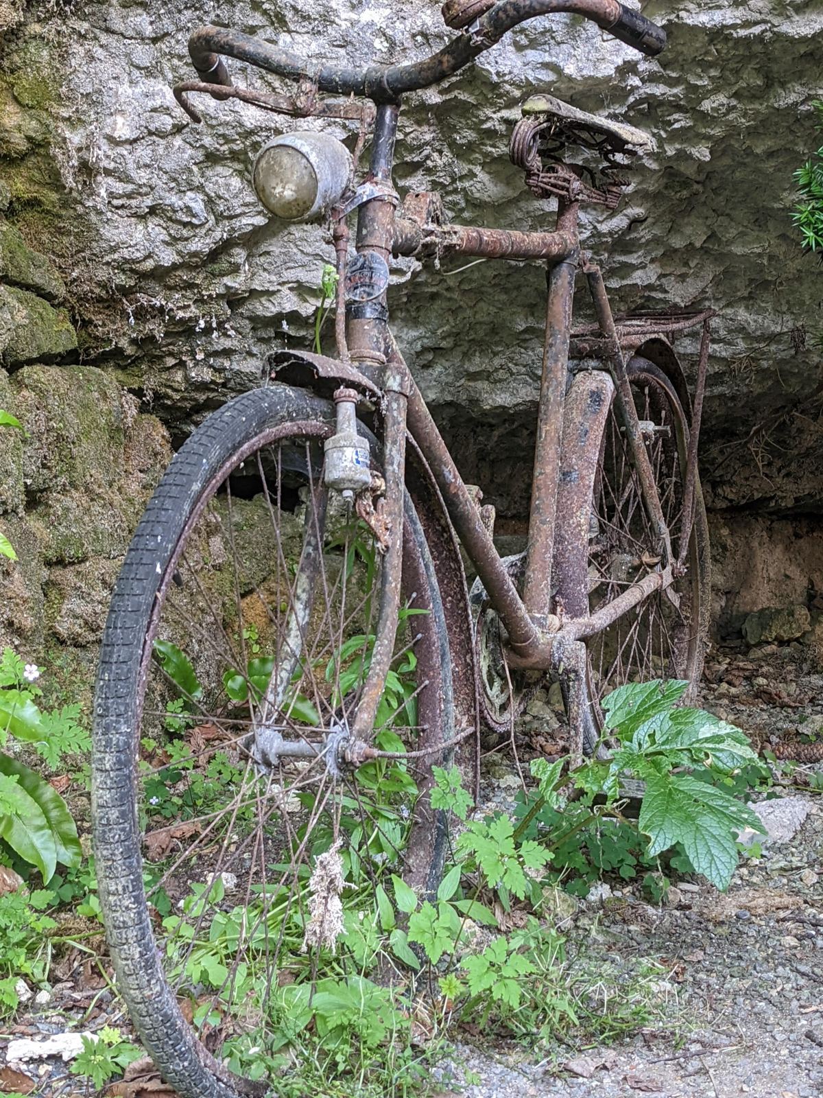 An old rusty bicycle propped in a rock overhang beside the road