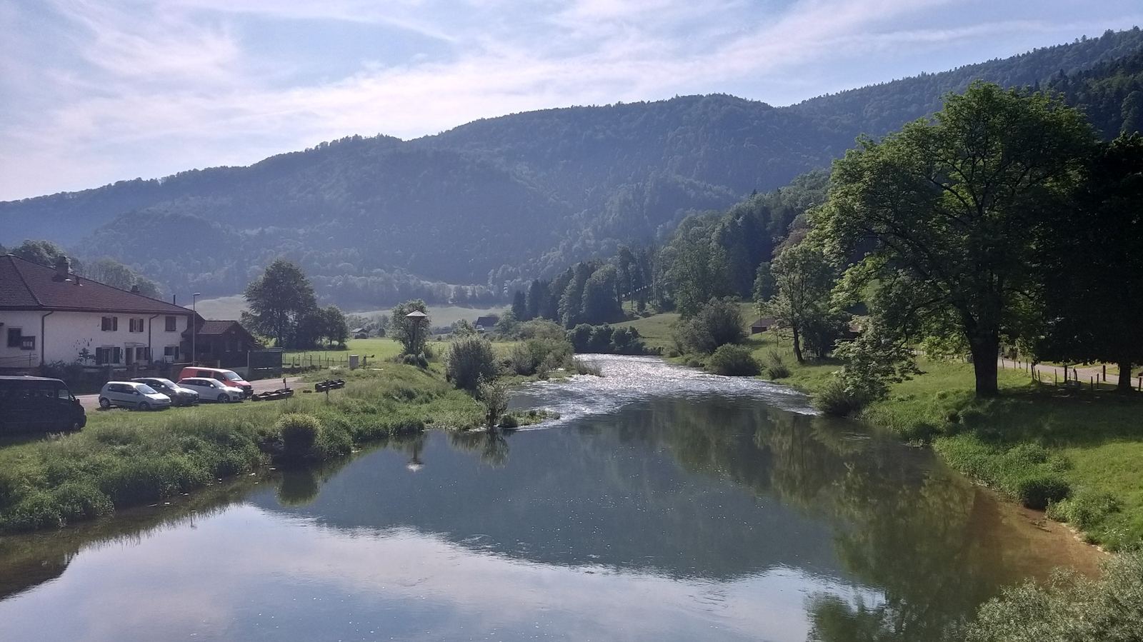 The calm Doubs at Soubey reflecting the trees and hills on a still morning