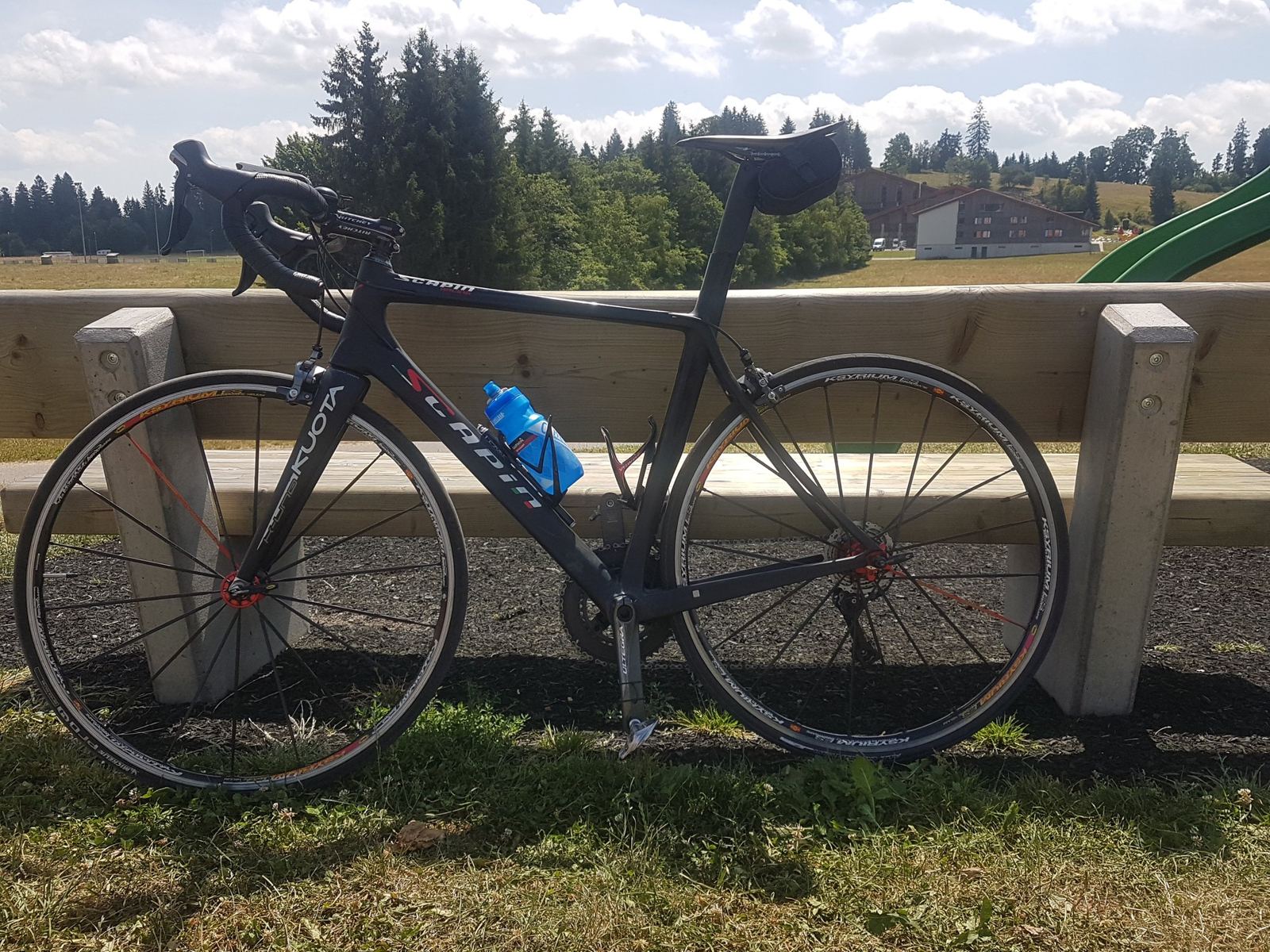 A road bike leaning on a bench on the open plateau near Saignelégier with forest behind