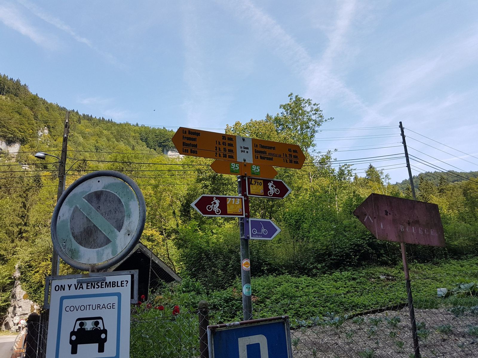 Yellow Swiss hiking signposts and a border sign by the road at La Goule