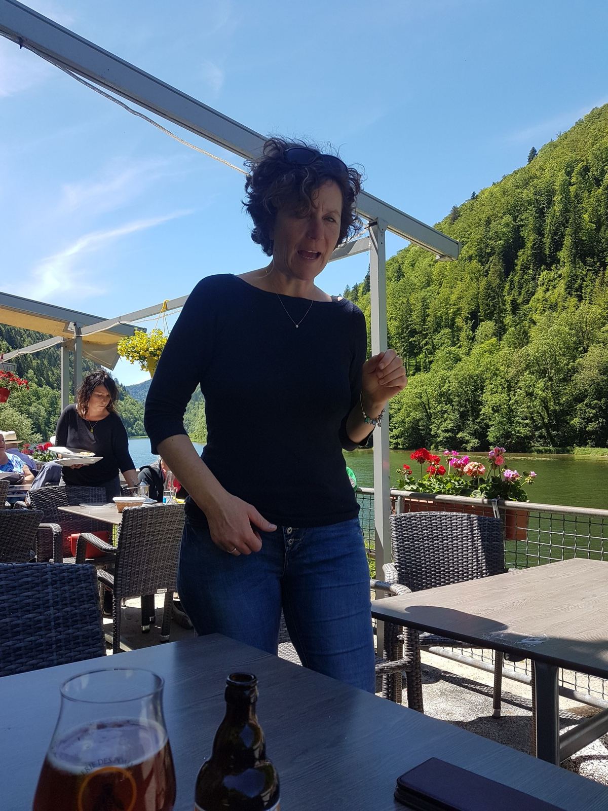 A woman standing on the restaurant terrace by the river at La Goule