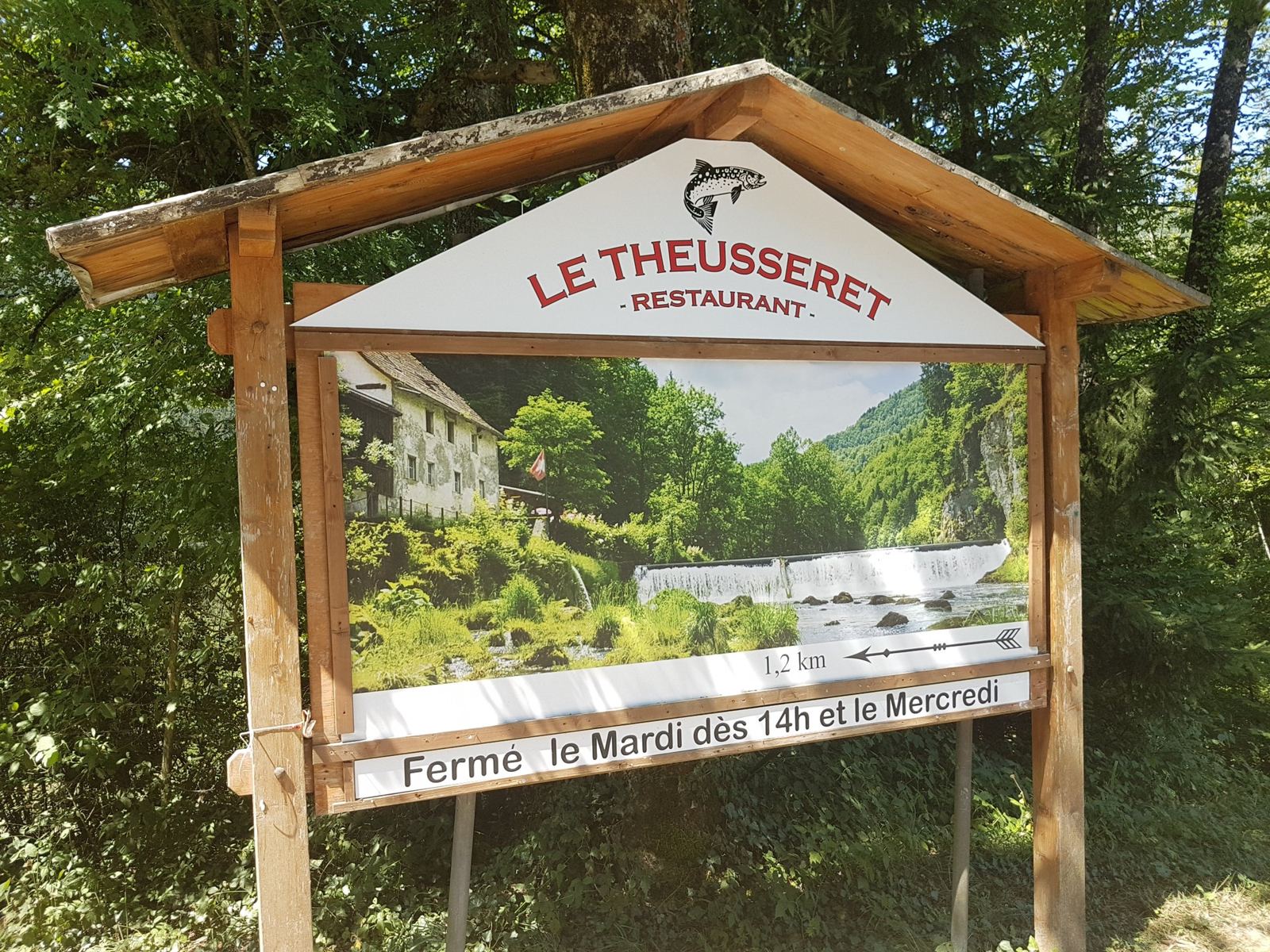A wooden sign for the Le Theusseret restaurant beside the Doubs