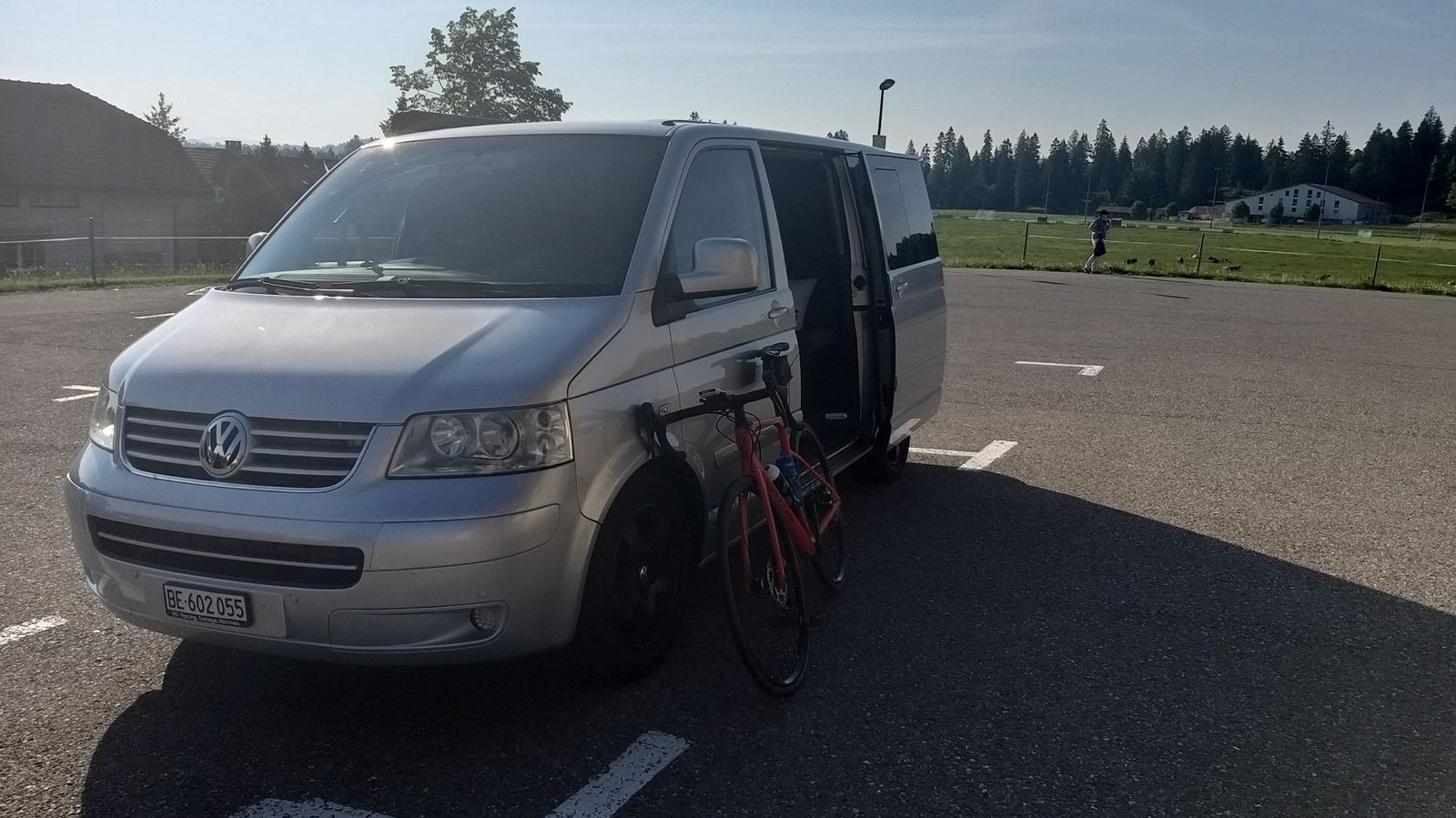 A silver VW T5 van parked at Saignelégier with a bike, early in the morning