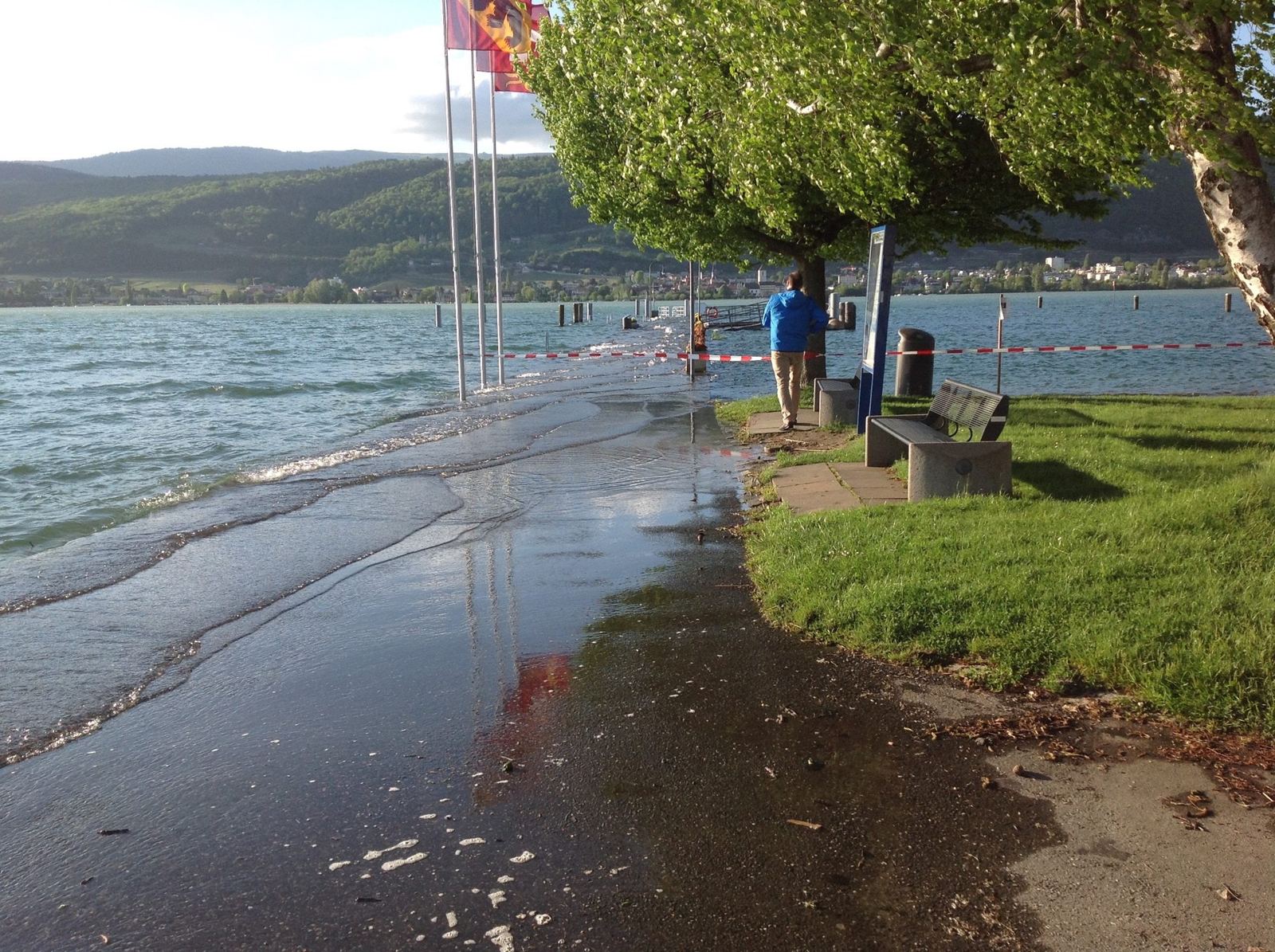 Lake Biel flooding over the shore path at Erlach, with water across the grass