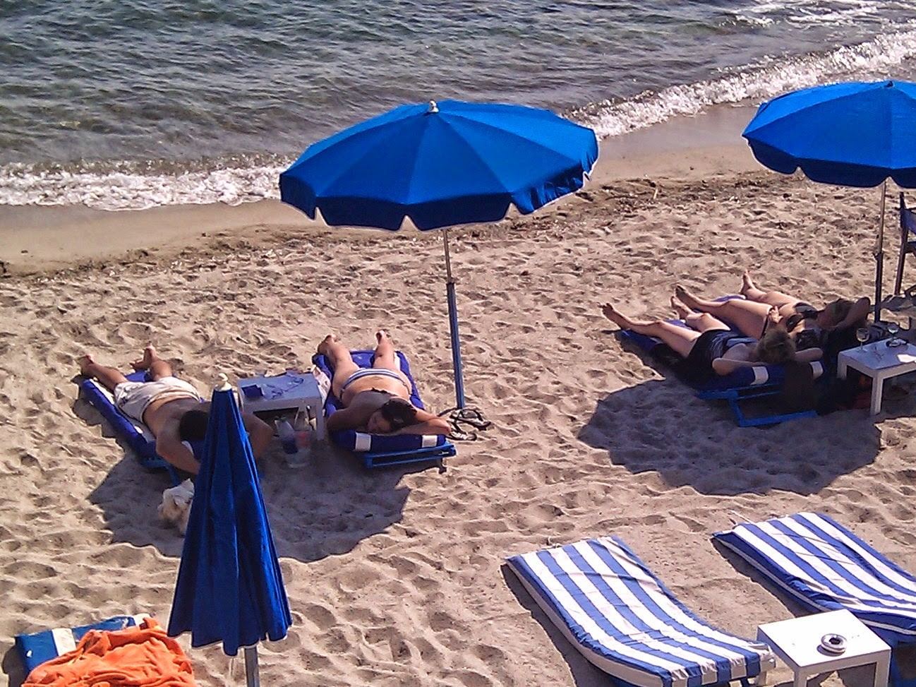 Blue parasols and striped sun loungers on a sandy beach