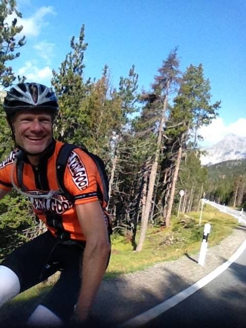 A cyclist in an orange Mr Feelgood jersey riding up the Ofen Pass road through the forest