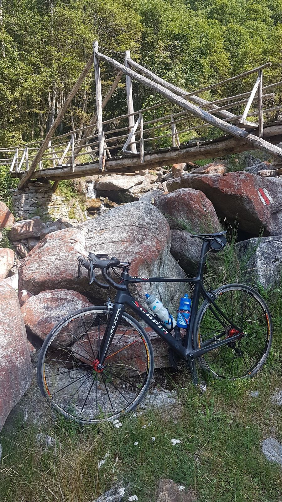 A road bike leaning against pink granite boulders beside an old wooden footbridge
