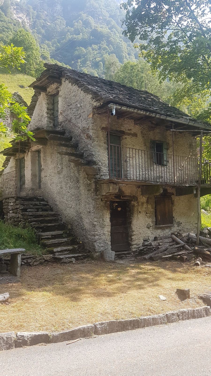 An old stone house with a wooden balcony and outside stairs in the Val d'Osura