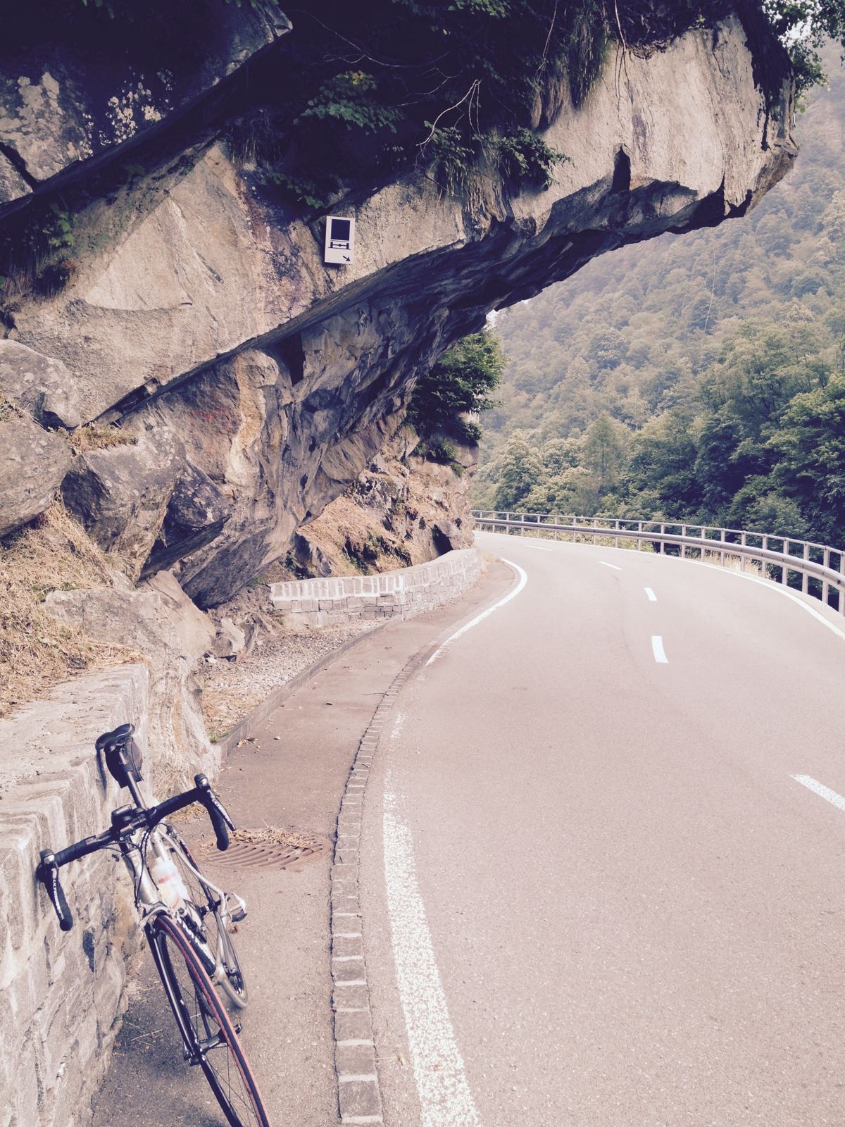 A road bike leaning against the rock wall where the valley road runs under an overhanging cliff