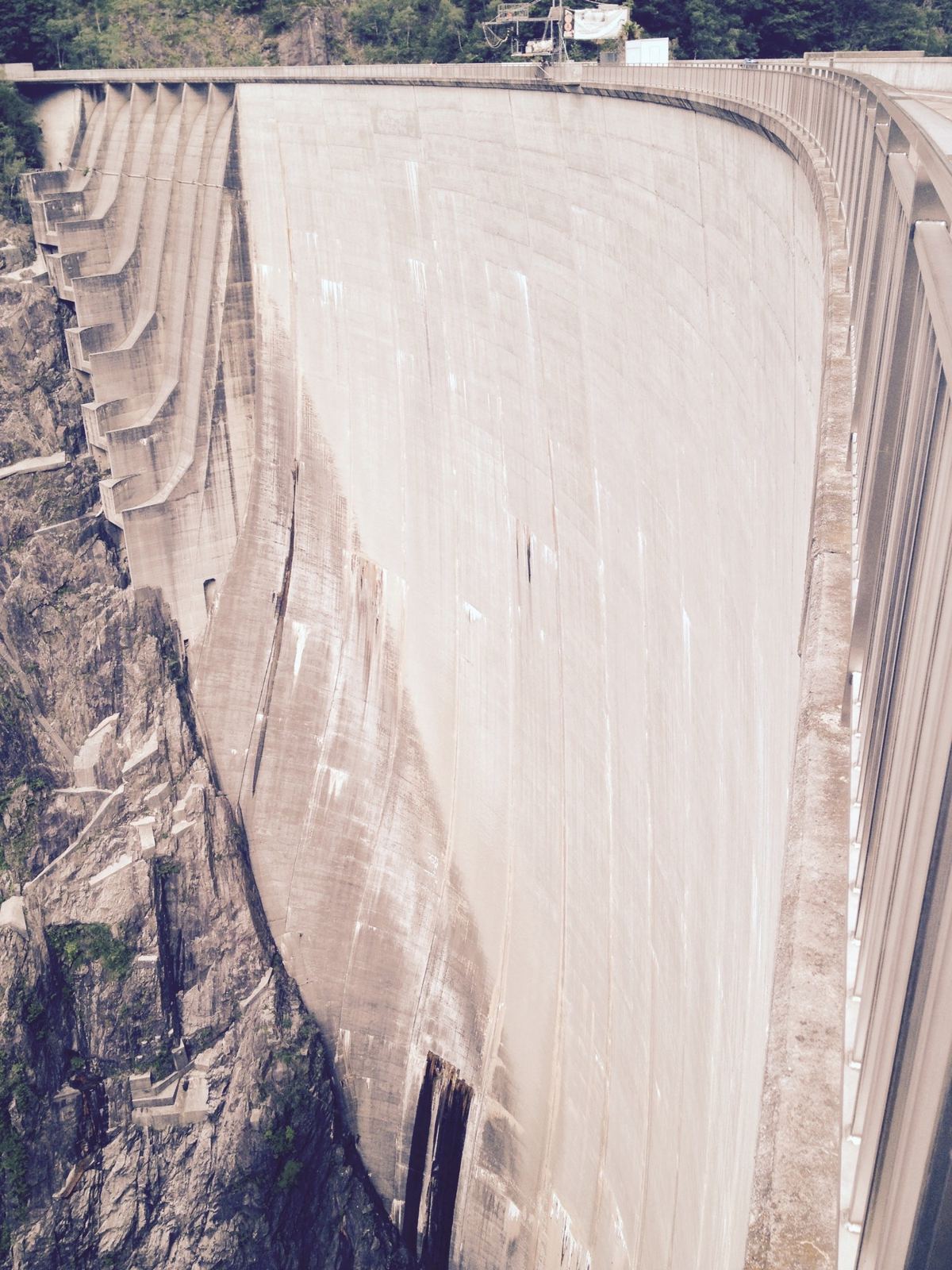The huge curved concrete wall of the Verzasca Dam seen from the top